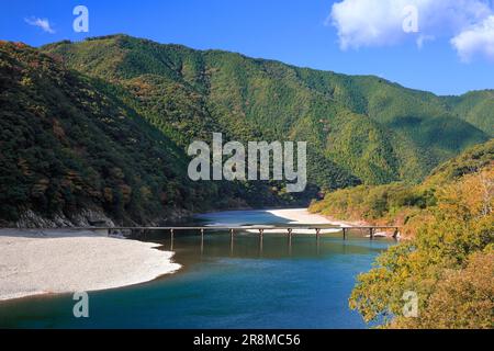 Eine Tiefwasserüberquerung und Herbstfarben zwischen Felsen im Shimantogawa River Stockfoto