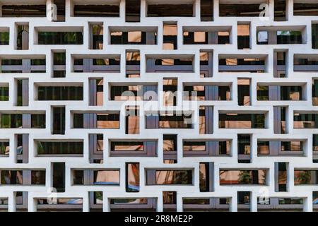 Ungewöhnliche Fassade des Gebäudes in Form von Quadraten und Glas mit Reflexionen des roten Himmels Stockfoto