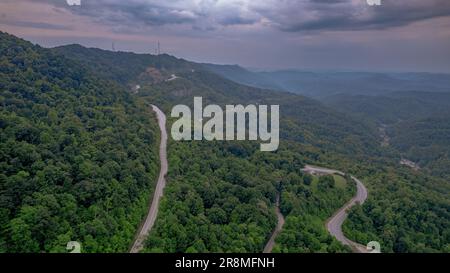 Eine Luftaufnahme einer malerischen gewundenen Straße, die sich durch einen üppigen grünen Wald erstreckt. Stockfoto