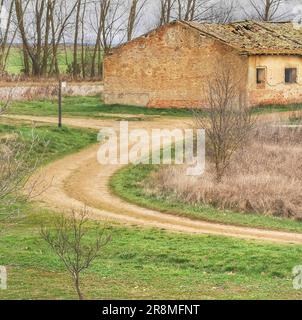 Eine malerische Landstraße schlängelt sich durch eine üppige, bewaldete Landschaft, gesäumt von zwei malerischen Hütten Stockfoto
