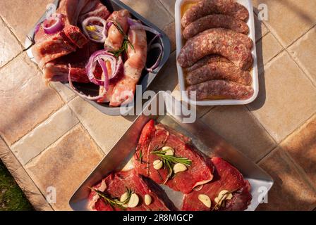 Verschiedene Arten von rohem Fleisch und Rindfleisch. Frisches rohes Fleisch auf einem Tisch im Freien, fertig zum Kochen. Stockfoto