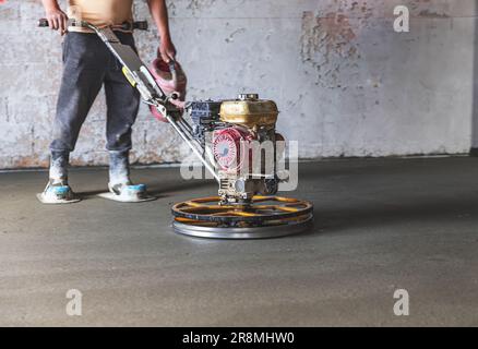 Bauarbeiter in einem Raum, der die Betonoberfläche schleift Stockfoto