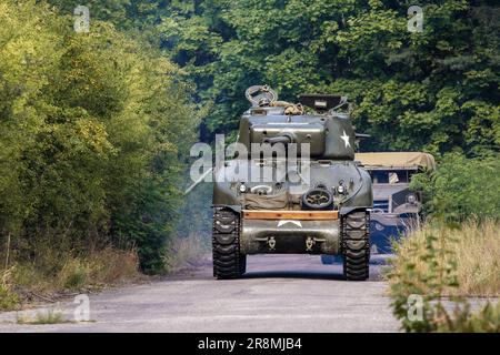 Ein amerikanischer Sherman aus dem Zweiten Weltkrieg fährt auf der Straße zwischen den Bäumen Stockfoto
