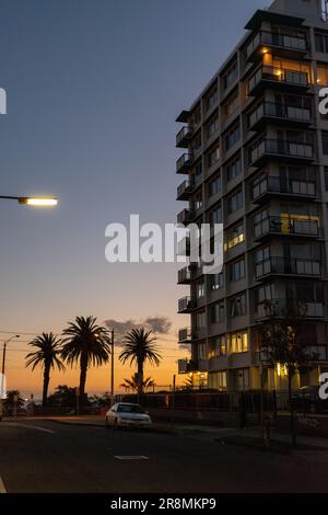 Ein vertikales Bild eines Wohnungsgebäudes in der Nähe von Palmen bei Sonnenuntergang Stockfoto