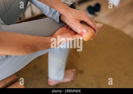 Nahaufnahme eines fußhaltenden Mannes mit Schmerzen an der Fusssohle, Massageblasen am Fuss mit Fingern. Männlicher mit Kallusschmerzen an der Ferse. Stockfoto