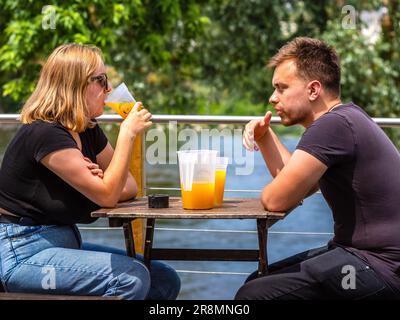 Junges Paar am Café-Tisch, das frischen Orangensaft trinkt - Tours, Indre-et-Loire (37), Frankreich. Stockfoto