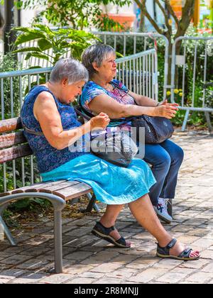 Zwei ältere Frauen, die sich auf einem Gartensitz im Stadtzentrum unterhalten - Tours, Indre-et-Loire (37), Frankreich. Stockfoto