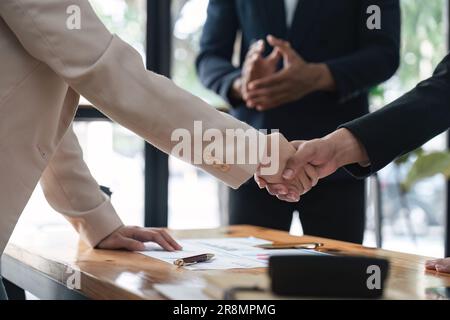 Ende des Händedrucks von zwei glücklichen Geschäftsleuten nach einer Vertragsvereinbarung zur Zusammenarbeit im Team. Kollegen applaudieren Stockfoto