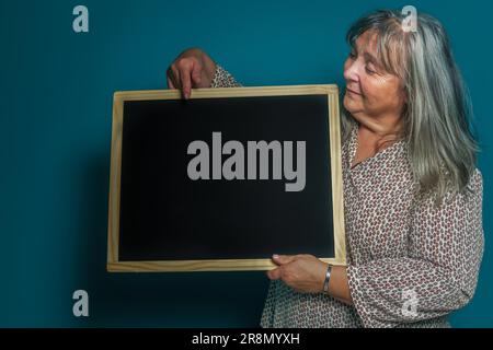 Ältere weißhaarige Frau hält eine Tafel mit Platz zum Kopieren von Text Stockfoto