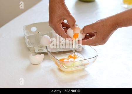 Eine Frau knackt Eier in Eine Schale Stockfoto
