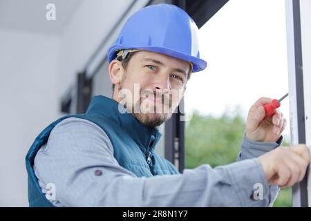 Junger Arbeiter im Zimmer mit großen Fenstern Stockfoto