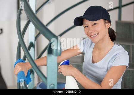 Glückliche Frau in Uniform, die im Büro Vorräte reinigt Stockfoto