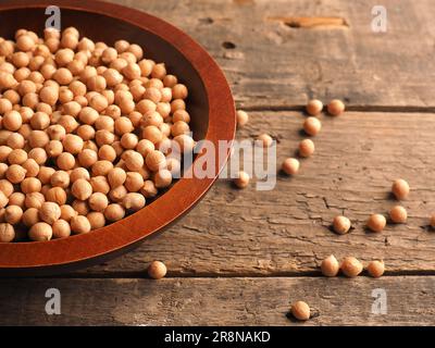 Bio getrocknete Kichererbsen in einer Holzschüssel auf einem rustikalen Holzküchentisch, vegetarisches Protein, gesunde Lebensmittel Stockfoto
