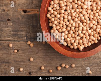 Bio getrocknete Kichererbsen in einer Holzschüssel auf einem rustikalen Holzküchentisch, vegetarisches Protein, gesunde Lebensmittel Stockfoto
