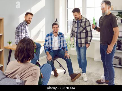 Glückliche männliche Freunde feiern, reden und Bier trinken, Spaß zusammen zu Hause haben. Stockfoto
