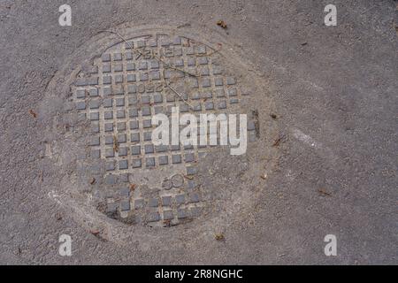 Schachtabdeckung auf Asphalt, mit Pollen und Staub bedeckt, Draufsicht Stockfoto