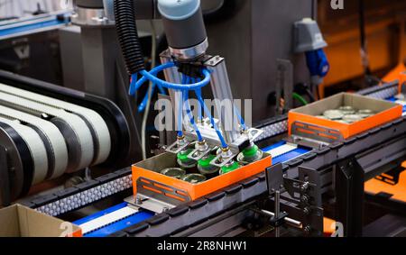 Automatisierter Roboterarm zum Anheben von Lebensmittelkannen zum Förderband in der Lebensmittelindustrie. Stockfoto