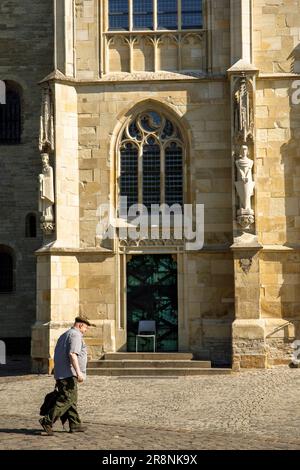 Ein Mann, der an der St. Paul's Cathedral, Münster, Nordrhein-Westfalen, Deutschland. Mann ging am der St. Paulus Dom vorbei, Münster, Nordrhein-Westfale Stockfoto