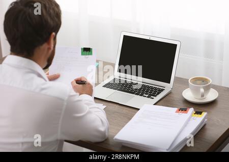 Geschäftsmann, der mit Dokumenten am Tisch im Büro arbeitet, Rückansicht Stockfoto