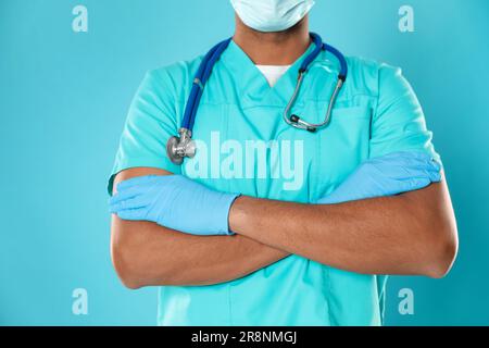 Arzt oder medizinische Assistentin (männliche Krankenschwester) in Uniform mit Stethoskop auf türkisfarbenem Hintergrund, Nahaufnahme Stockfoto