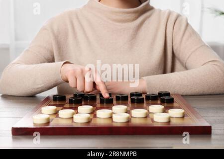 Dame spielen. Eine Frau, die über den nächsten Schritt am Tisch im Raum nachdenkt, die Schließung Stockfoto