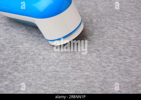 Moderner Rasierer auf hellgrauem Tuch mit Fusseln, Nahaufnahme. Platz für Text Stockfoto