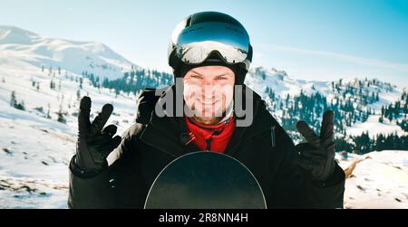 Nahaufnahme Porträt eines weißen Mannes mit dem Spiegelbild von schneebedeckten Bergen, weißen Pisten und Skigebiet. Eine Bergkette, die sich in der Skimaske widerspiegelt. Portr Stockfoto