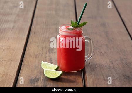 Köstliches Wassermelonengetränk im Maurerglas und frische Limette auf einem Holztisch Stockfoto