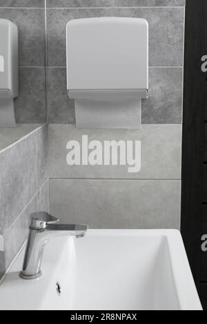 Neuer Papierhandtuchspender, der an der Wand im Badezimmer hängt Stockfoto