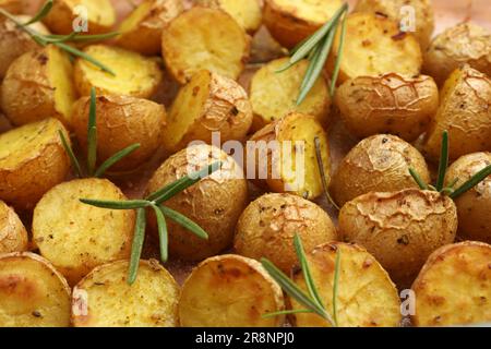 Leckere Backkartoffeln mit Rosmarin als Hintergrund, Nahaufnahme Stockfoto