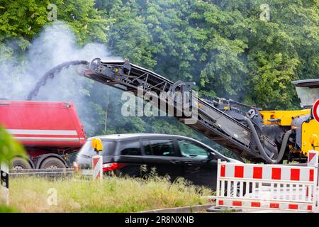 Asphalt-Fräs- und Schleifmaschine auf der Straßen- und Baustelle, die alte Bitumen in großen schweren Müllkipper wirft Stockfoto