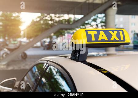Nahaufnahme Detail gelbe Taxi-Symbol auf Autos Dach stehen am Parkplatz des Flughafenterminals oder Bahnhof gegen Park warmen Abend Bokeh warten Stockfoto