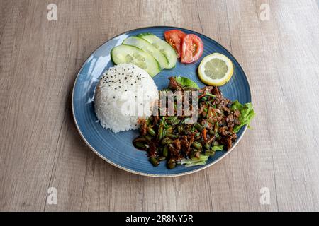 Asiatische Dishe kulinarisches Stillleben. Thai-Basilikum mit weißem Reis, Paprika, mariniertem Rinderfilet mit Basilikumsauce, in einem Wok gebraten Stockfoto