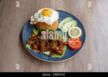 Asiatische Dishe kulinarisches Stillleben. Loc Lac mit Hackfleisch, im Wok gebraten, Reis, Tomaten, Gurken und Zitrone Stockfoto