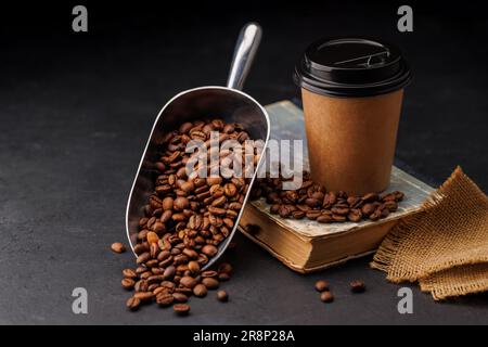 Aromatischer Kaffee in einem Pappbecher und frisch geröstete Kaffeebohnen Stockfoto