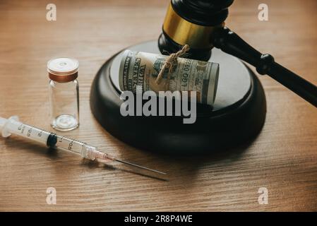 Selektiver Fokus von Spritze, Impfstoff, Hammer und Bargeld. Stockfoto