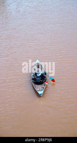 Angler, die in der Mitte des Flusses mit einem kleinen Boot paddeln Stockfoto