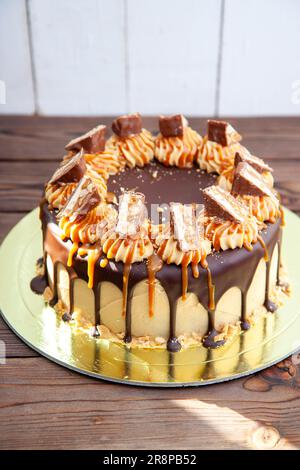 Herrlicher Snickers-Kuchen mit Erdnussbutter-Sahne, geschmolzener Schokolade, Schokoriegeln und gesalzenem Karamell Stockfoto