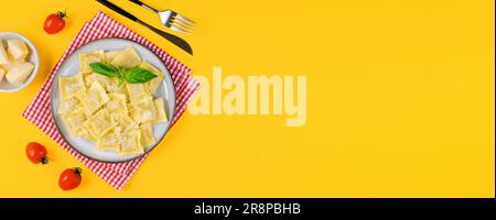Leckeres, appetitliches Ravioli mit Käse und Basilikum auf einem Teller, hellgelber Hintergrund Stockfoto
