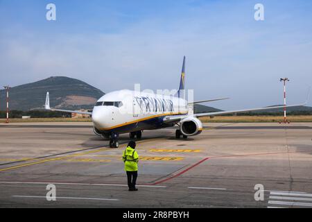 ALGHERO, ITALIEN - 30. MAI 2023: Bodenbesatzungsflughafen Marshaller wartet auf Boeing 737-800 Flugzeug der Billigfluggesellschaft Ryanair, das am Gate in Al ankommt Stockfoto