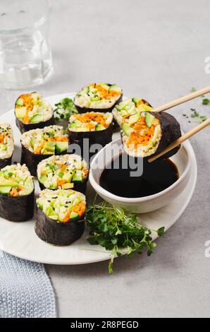 Vegane Sushi Rolls mit frischem Gemüse und Quinoa, leckere vegetarische Mahlzeit auf hellem Hintergrund Stockfoto