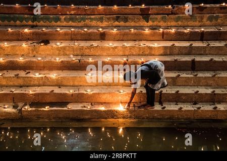 Ein Mädchen zündet Öllampen in Gauri Kund an den Ghats von Varanasi, Indien Stockfoto