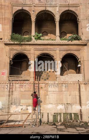 Ein Sadhu klettert von seiner Unterkunft auf den Ghats von Varanasi, Indien Stockfoto