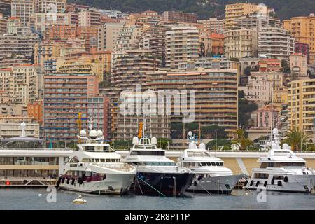 Monaco - 2. Februar 2016: Luxusjachten liegen im Hafen von Hercule an den Wolkenkratzern am Wintertag im Hintergrund vor. Stockfoto