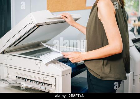 Vertrauensvolle Sekretärin, die mit modernen Druckern arbeitet und im Unternehmen arbeitet Stockfoto