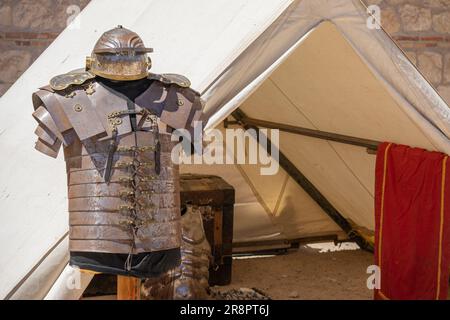 Horizontale Ansicht im Vordergrund eines Ausstellers mit Rüstung und kaiserlichem Helm eines Soldaten aus dem antiken römischen Reich vor einem Militärzelt, Loric Stockfoto