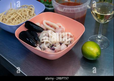 Rohe Zutaten zum Kochen von Meeresfrüchte-Pasta - Spaghetti, Muscheln, Sauce, Limette, Tomaten und Weißwein Stockfoto