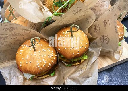 Gegrillter Burger mit Rindfleisch, Tomaten, Käse, Gurke und Salat. Fastfood zum Mittagessen. Essen. Сatering. Stockfoto