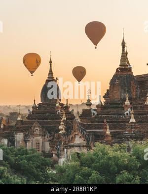 Heißluftballons zwischen Tempeln bei Sonnenaufgang in Old Bagan, Myanmar. Stockfoto