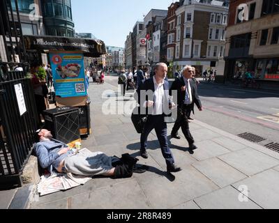 Geeignete Pendler, die an einem schlafenden Obdachlosen an der Liverpool Street Station London vorbeilaufen Stockfoto